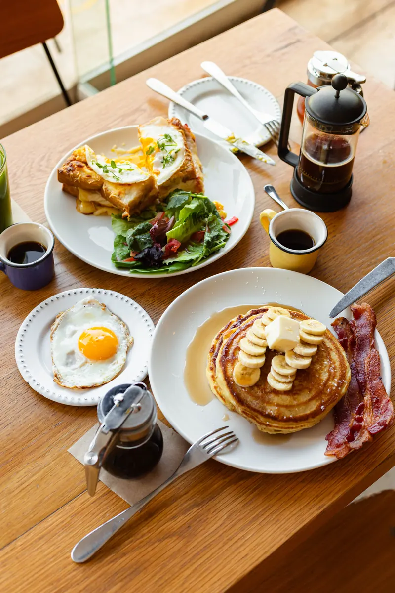 Desayuno en Merci: banana pancakes con tocino, Croque Monsieur con huevo y ensalada, huevo estrellado y café en french press